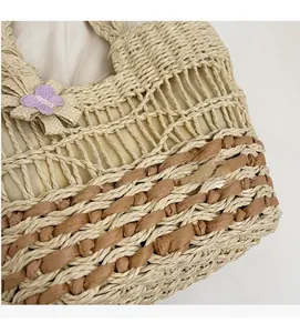Détail du motif de tressage en paille bicolore avec un papillon décoratif en tricot violet