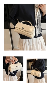 Detailed view of cream-white rectangle flap handbag with silver metal buckle and top handle