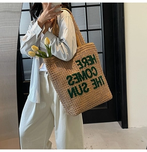 Detail of woven straw tote bag with Here Comes The Sun green letter embroidery