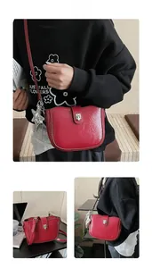 Close-up of wine red saddle bag with silver star charm and metallic twist-lock detail