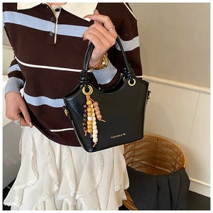 Detail of black bucket bag featuring decorative colorful wooden beads and knotted handle