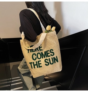 Detail of hand-woven straw tote with green embroidery and comfortable canvas shoulder strap
