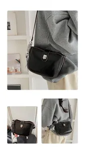 Detail of black textured crossbody bag with silver star charm and contrast brown edges