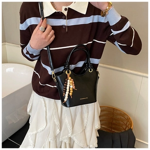 Detalle del bolso cubo negro con borlas de cuentas de madera de colores y aros dorados