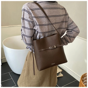 Gros plan d'un sac seau en cuir marron rétro avec texture litchi et boucle en métal