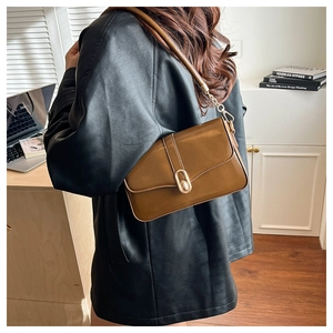 Deep brown glossy patent leather shoulder bag detail with gold oval buckle and chain strap