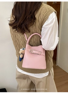 Pink lychee grain leather bucket bag featuring a cute teddy bear charm and metal buckle