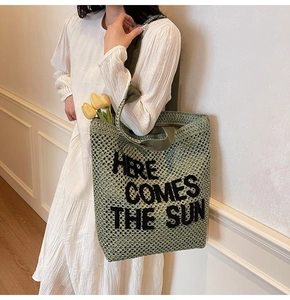 Green crochet tote bag detail with Here Comes The Sun black letter embroidery