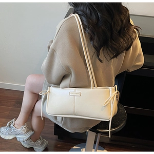 Detail of cream baguette bag with double straps and side bow ribbon accents for women