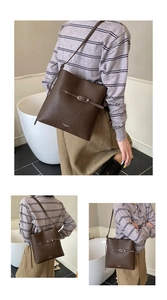 Détail du sac seau en cuir marron foncé avec boucle argentée et logo doré