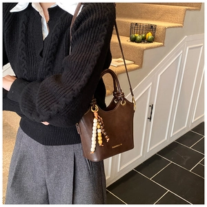 Dark brown leather bucket bag with wooden bead tassel and crossbody strap detail