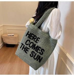 Detail of mint green crochet tote bag featuring Here Comes The Sun text and woven texture