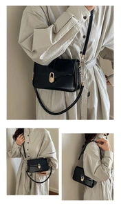 Detail of a minimalist black leather underarm bag featuring a unique oval gold buckle