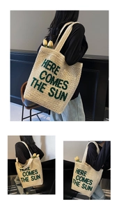 Detail of cream woven shoulder bag featuring green Here Comes The Sun embroidery