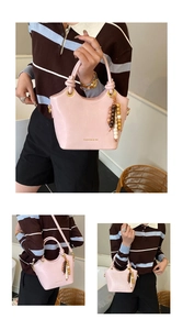 Detalle del bolso tipo cubo de cuero rosa con letras de moda y dijes de madera