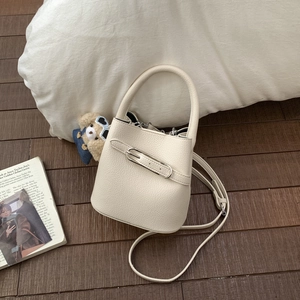 Detail of creamy white pebble leather bucket bag with silver buckle and cute bear charm