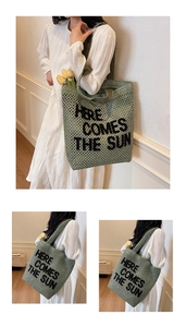 Detail of green knit tote bag with Here Comes The Sun lettering and crochet texture