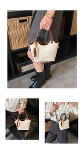 Detalle del bolso tipo cubo blanco crema con asas marrones y elegante colgante de perlas
