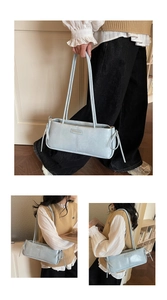 Detail view of light blue baguette shoulder bag with metal plate and sleek PU leather texture