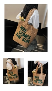Detail of woven tote bag with green embroidered text on hollow mesh texture