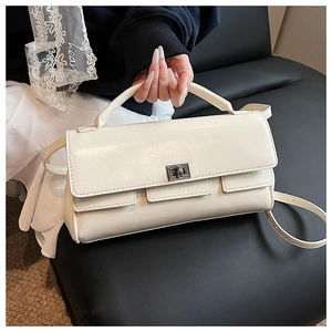 Detail of cream rectangular handbag featuring a silver twist lock and smooth faux leather