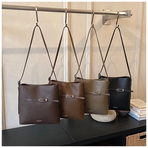 Sacs seau en cuir grainé en café, marron, vert et noir suspendus sur un support chic