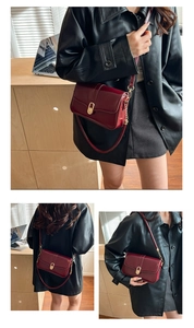Macro view of burgundy patent leather bag showing golden oval twist lock and sleek texture