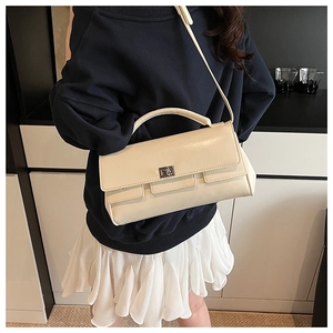 Close-up of cream rectangular flap bag with silver twist lock and leather handle strap
