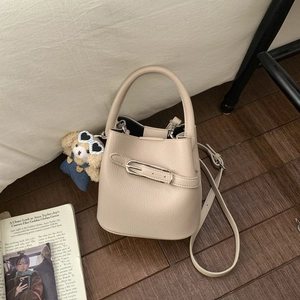 Close-up of beige lychee texture bucket bag with metal buckle and detachable shoulder strap