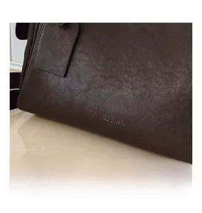 Dettaglio macro della pelle vintage marrone scuro con logo Cahres & Heka in rilievo