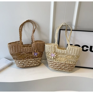 Détail de sacs à bandoulière en paille tressée avec texture résille et pendentif floral en deux tons