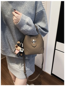 Taupe pebbled leather bucket bag with silver turn-lock clasp and cute black dog charm