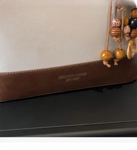 Detail of beige tote bag featuring brown leather base stitching and retro wooden bead tassel