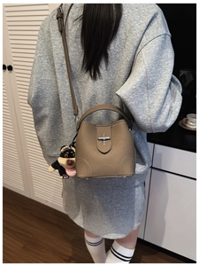 Brown lychee leather bucket bag with silver lock and dog charm on a female model