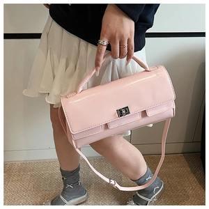 Detail view of pink patent leather handbag with silver twist lock and shoulder strap