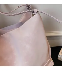 Close-up of soft matte leather texture and stitching on a light pink tote bag