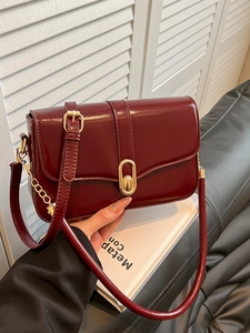 Minimalist glossy wine red leather crossbody bag with elegant gold oval buckle and chain