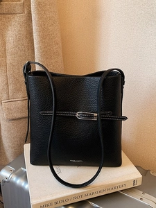 Sac seau minimaliste en cuir grainé noir avec boucle argentée sur fond texturé