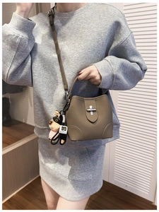 Detail of brown litchi pattern bucket bag with silver twist lock and cute dog pendant