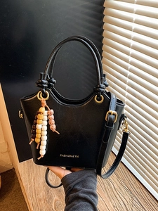 Chic black bucket handbag with beaded charm and adjustable strap for crossbody wear