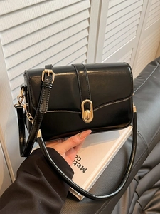 Minimalist black patent leather crossbody bag with golden hardware and adjustable strap