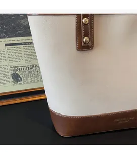 Detail view of cream and brown leather tote showing texture and gold rivet studs