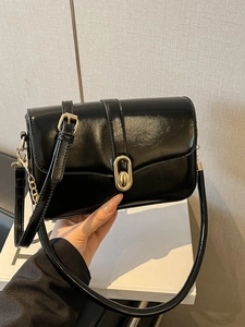 Minimalist black glossy leather crossbody bag with elegant gold oval twist lock closure