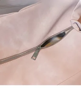 Detail of smooth silver zipper hardware on light pink large tote bag textured fabric