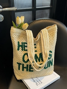 Beige woven straw tote bag with green embroidered Here Comes The Sun slogan for summer beach