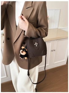 Detail of dark brown leather bucket bag with silver twist lock and plush puppy charm
