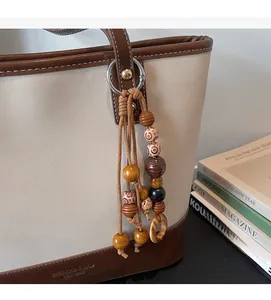 Detail of retro contrast tote bag with stylish wooden bead pendant and embossed logo