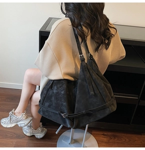 Detail view of a large black suede hobo bag showing its minimalist slouchy silhouette