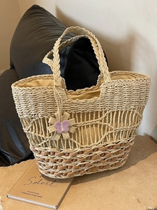 Sac cabas en paille tissée avec poignées tressées et breloque fleur sur pierre