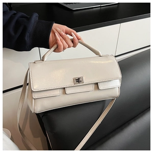 Detail of a beige leather flap handbag featuring a silver twist lock and layered design